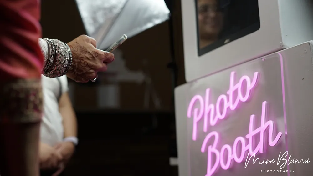 Guest enjoying the Photo Booth beside a neon sign